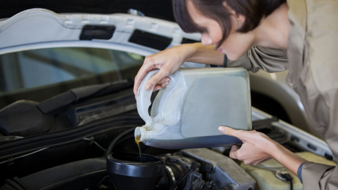 Moteris mechanikė pila automobilio alyvą į variklį